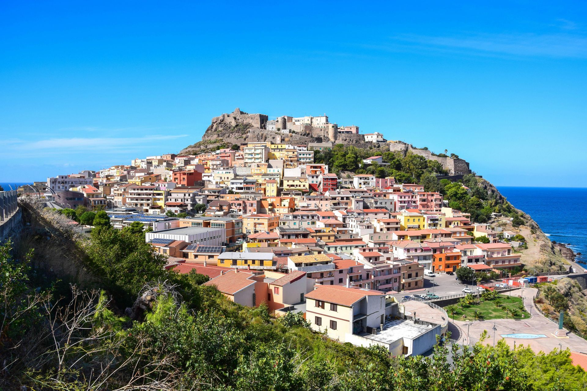 A small town is sitting on top of a hill next to the ocean.