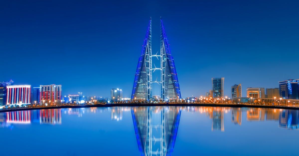 A city skyline at night with a large building in the middle of the water.