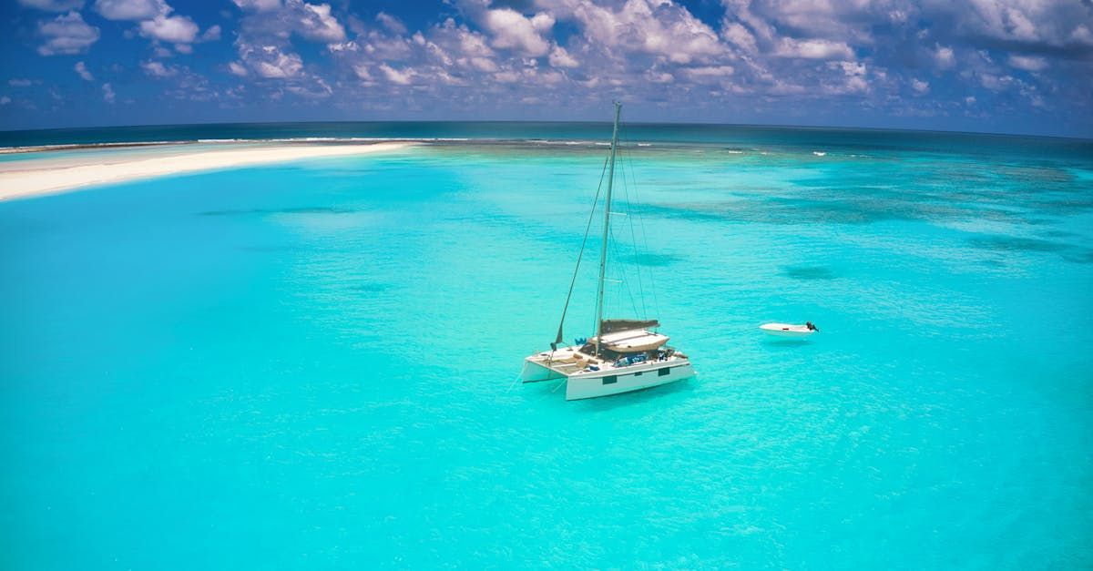 A sailboat is floating on top of a turquoise ocean.