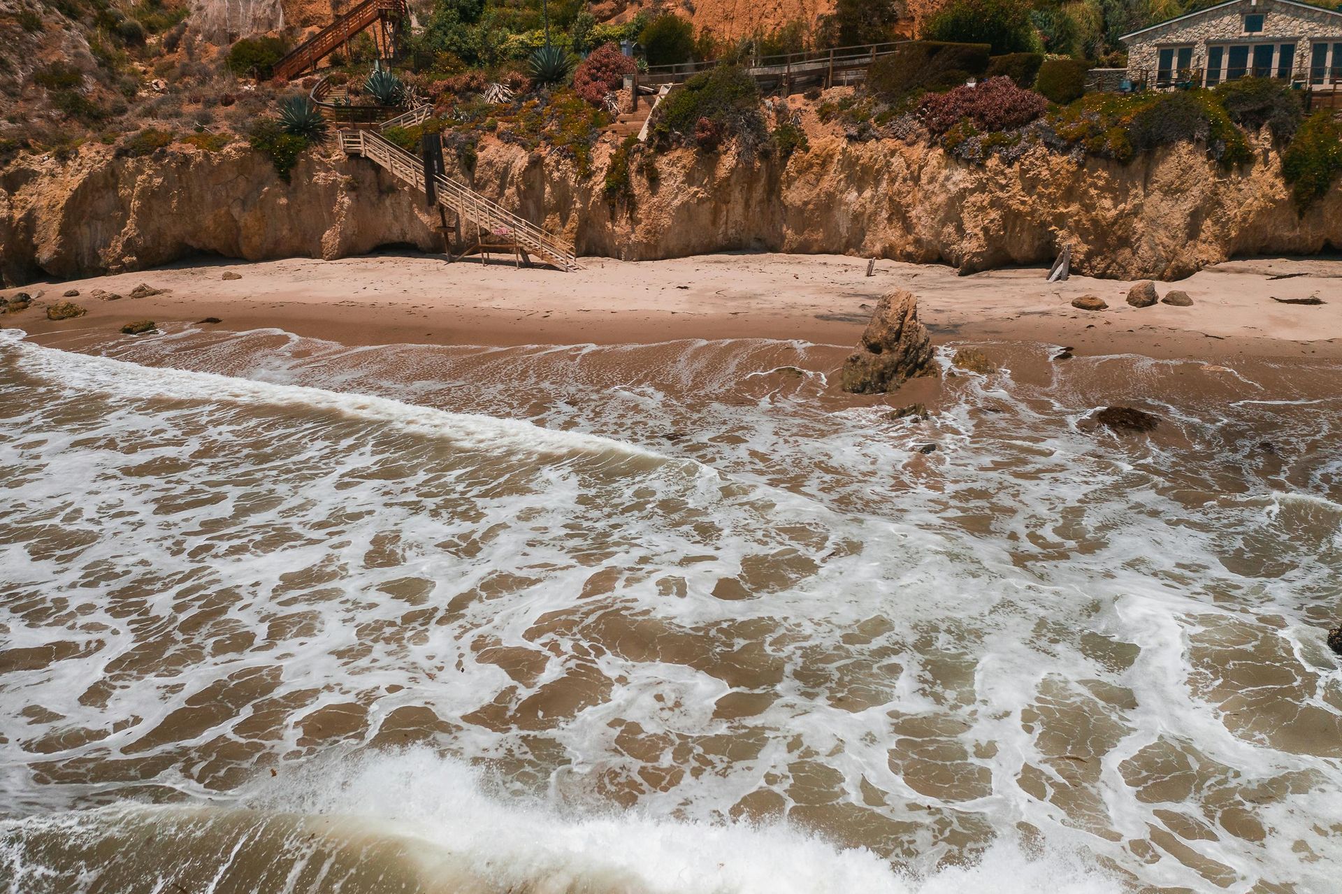 Waves crashing on a sandy beach with a cliff in the background