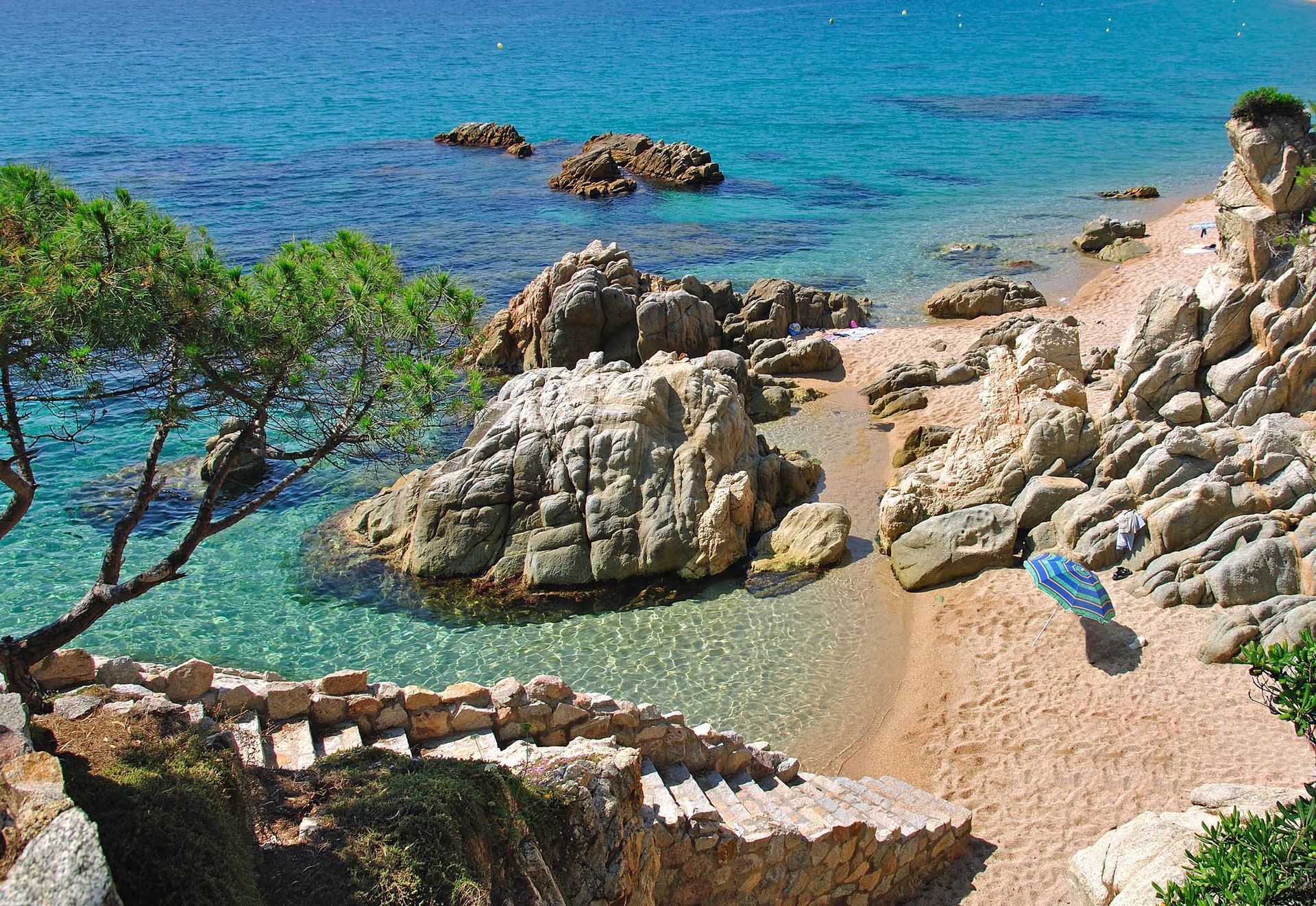 A beach with rocks and stairs leading to the ocean
