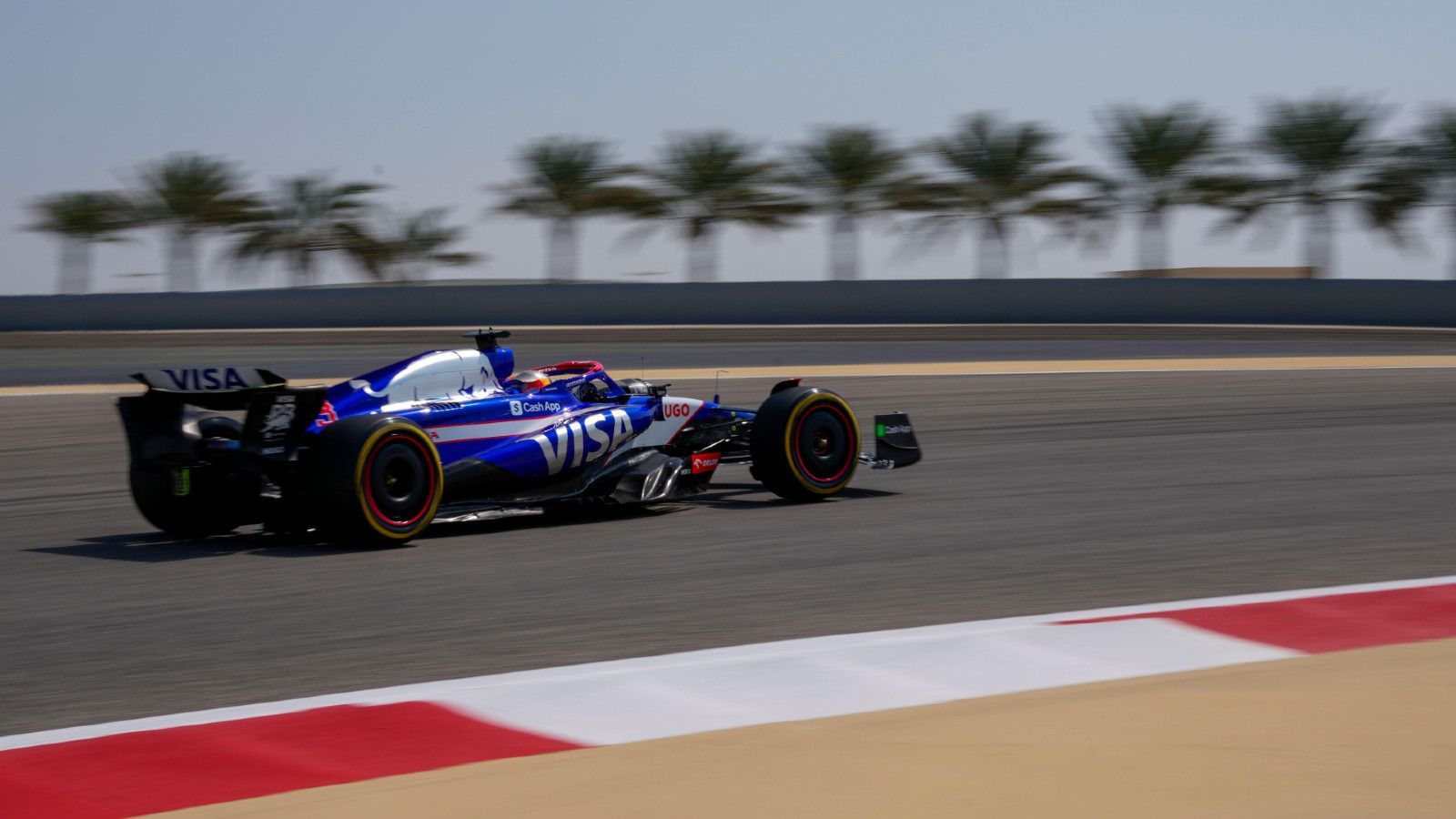 A blue and white race car is driving down a race track.