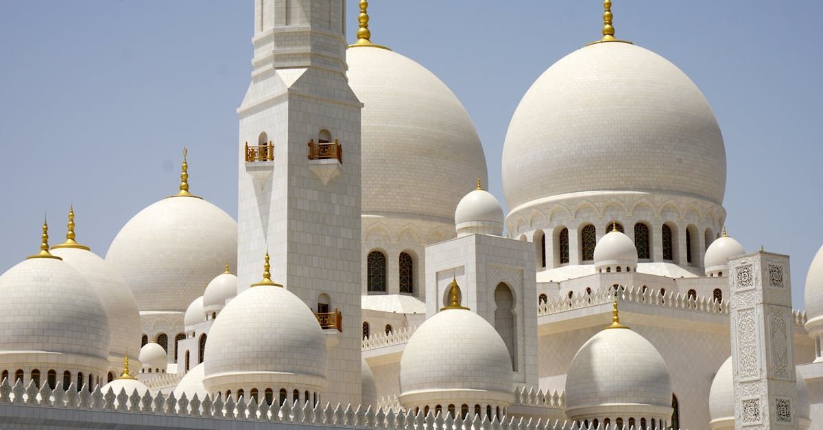 A mosque with a lot of white domes and a clock tower