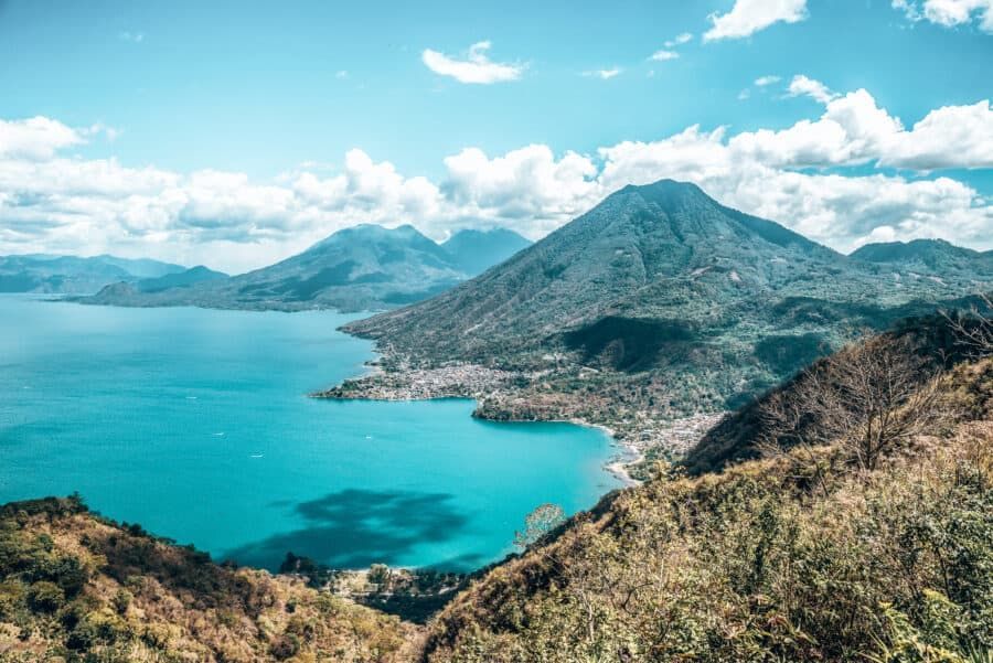 A lake surrounded by mountains and trees with a mountain in the background.