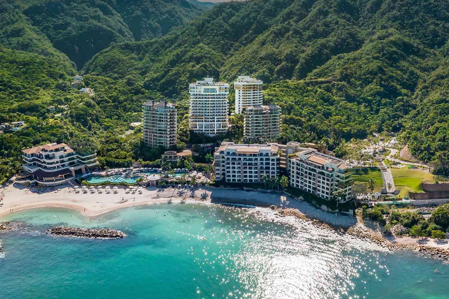 An aerial view of a tropical resort surrounded by water and mountains.