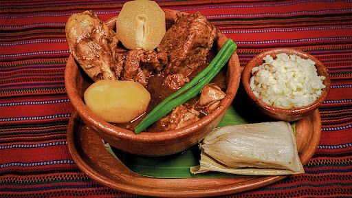 A bowl of food with green beans and potatoes on a plate on a table.