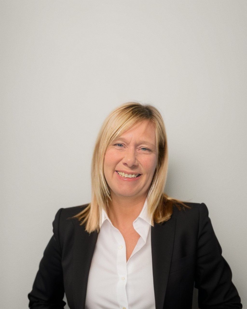 A woman in a black jacket and white shirt is smiling for the camera.