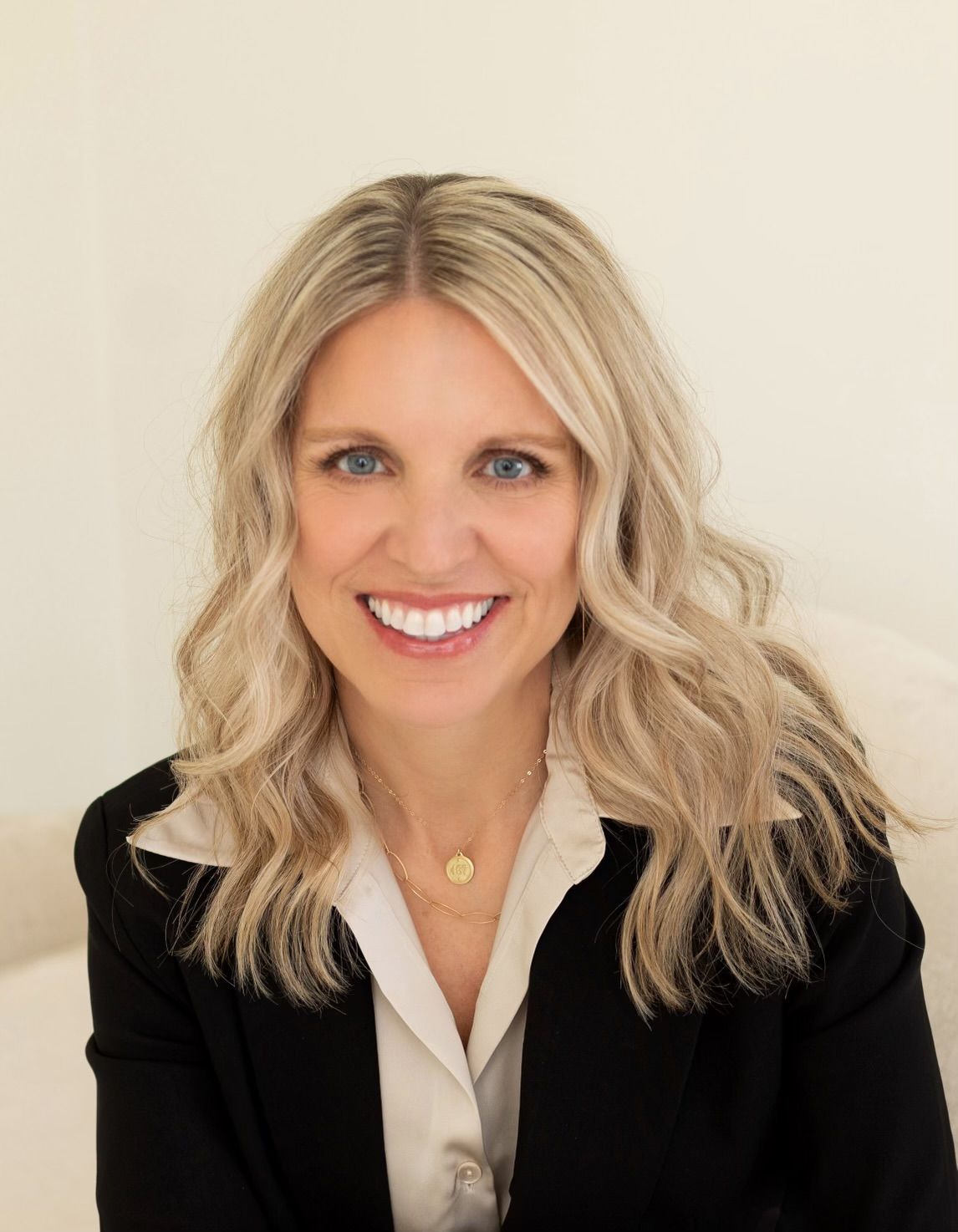 a woman in a black jacket and white shirt is smiling for the camera .