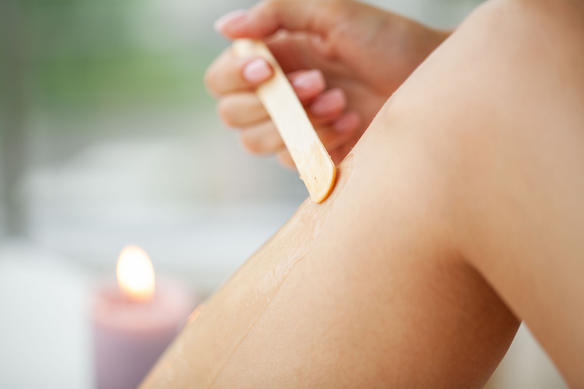 A woman is waxing her legs with a wax stick.