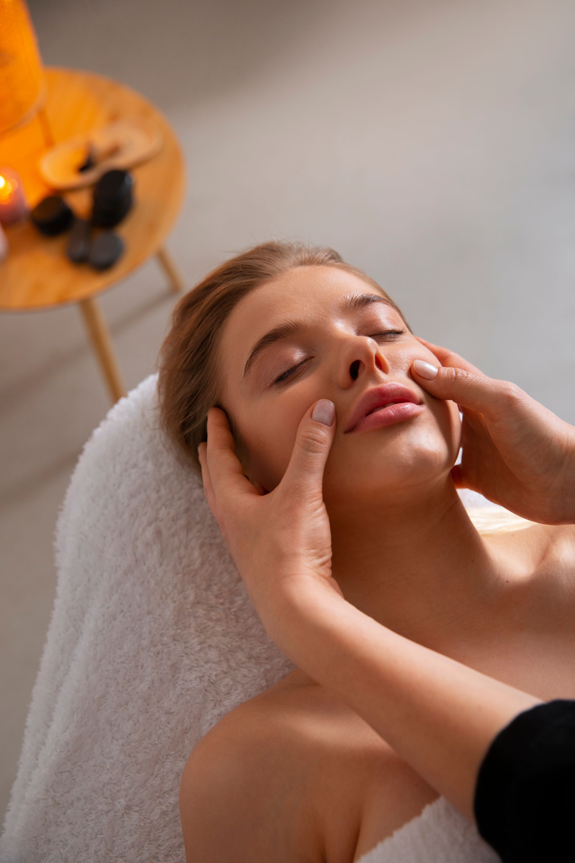 A woman is getting a facial massage at a spa.