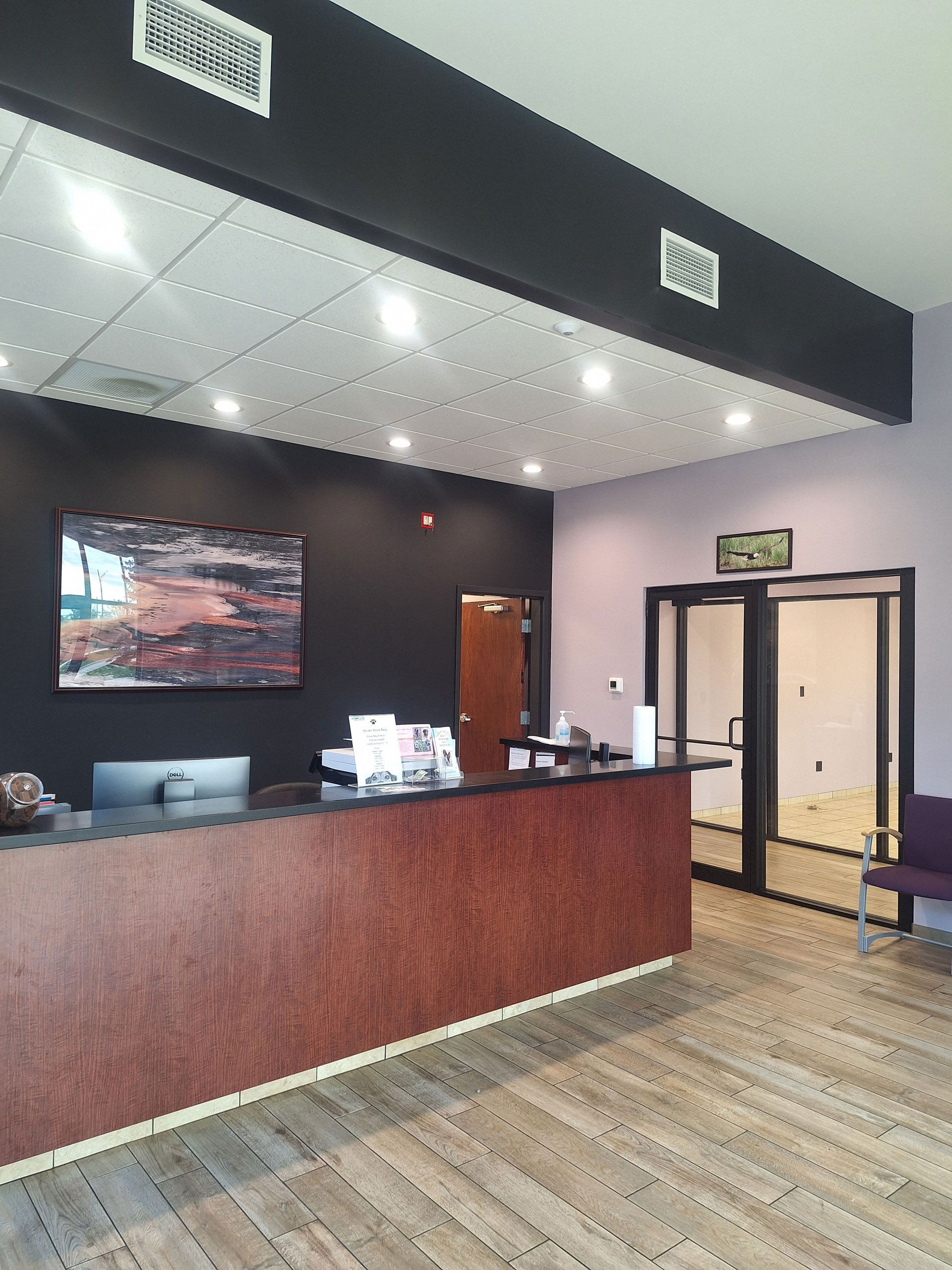 A reception area with a wooden counter and a painting on the wall