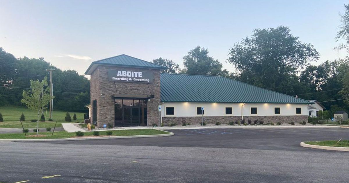 A large building with a green roof is sitting in the middle of a parking lot.