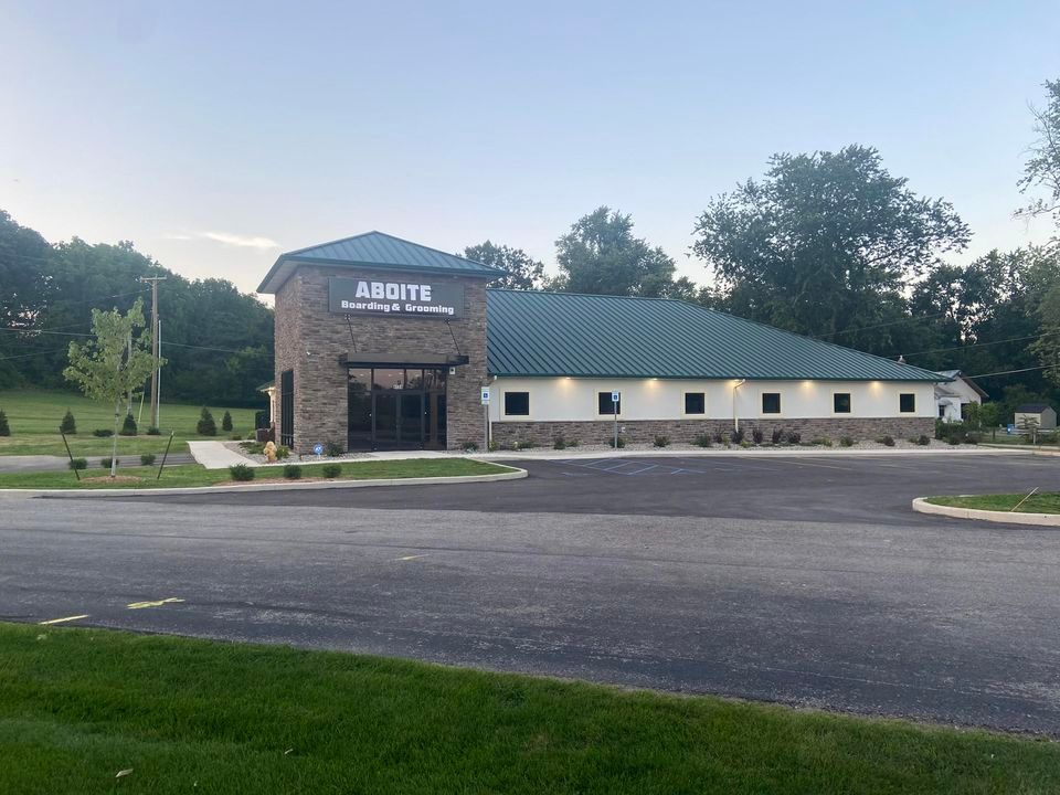 A large building with a green roof is sitting next to a road.