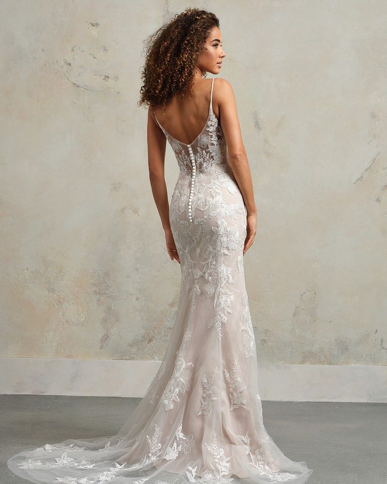 A woman in a white wedding dress is standing in front of a mountain.