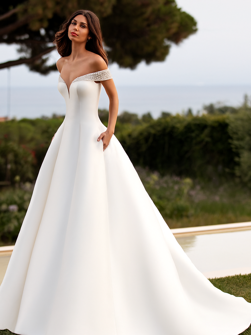 A woman in a white wedding dress is standing in front of a pool