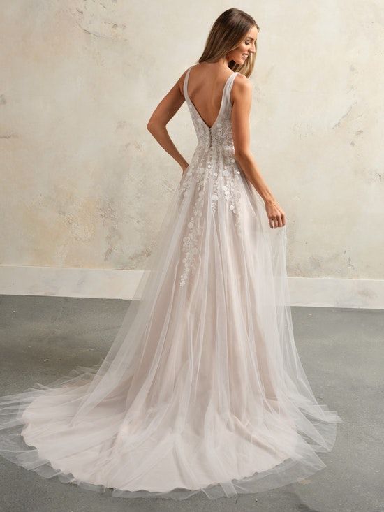 A woman in a wedding dress is standing in front of a wall.