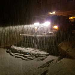 Truck with now plow clearing the driveway during the snow at night