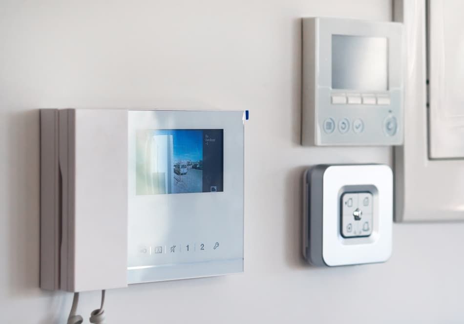 A White Video Doorbell Is Hanging On A White Wall Next To A Clock — Advanced Alarms Mackay Pty Ltd In South Mackay, QLD