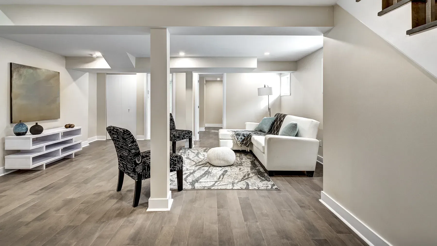 A modern basement remodel with laminate floors and a white couch