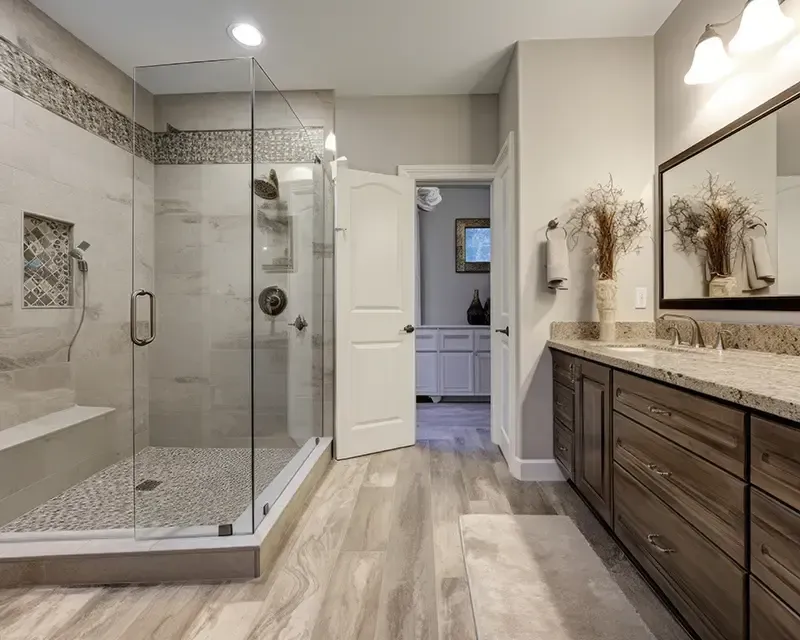 Modern bathroom with glass shower, double vanity, and light wood flooring