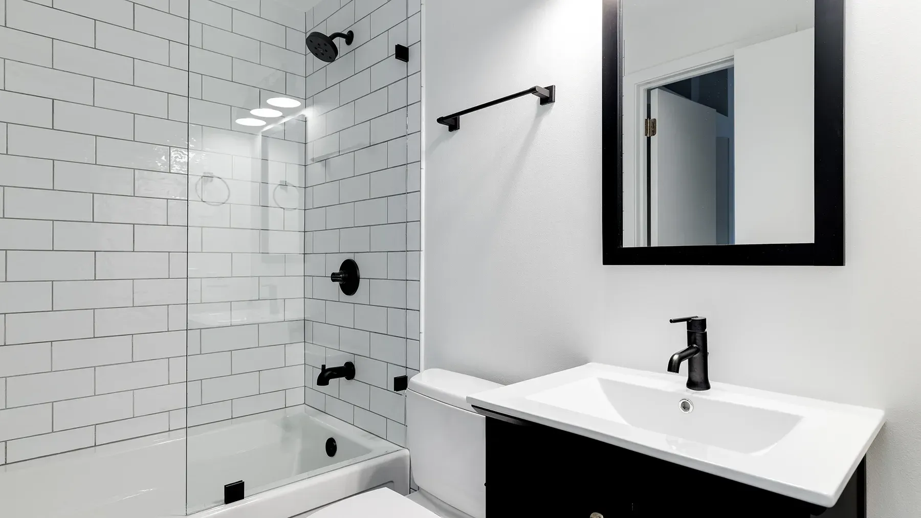 A small bathroom with a black and white color scheme and subway tiles