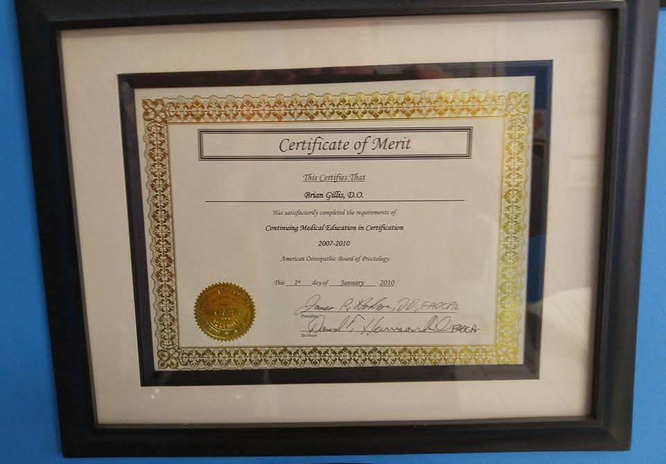 A certificate of merit is framed on a blue wall