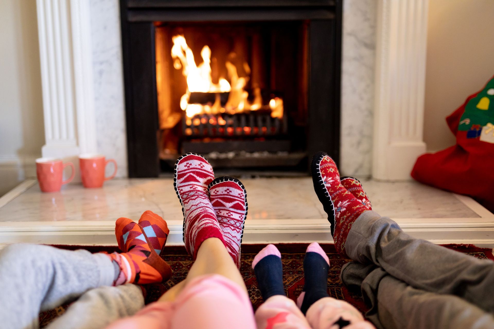 A family is sitting in front of a fireplace wearing socks.