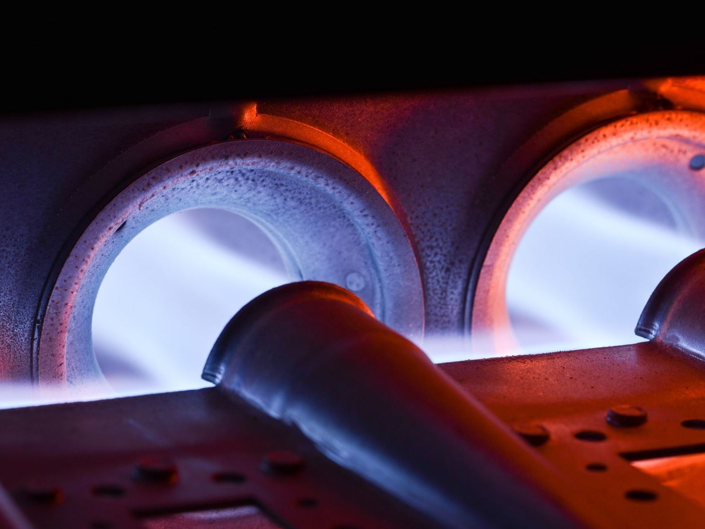 A close up of a gas burner with blue flames coming out of it.