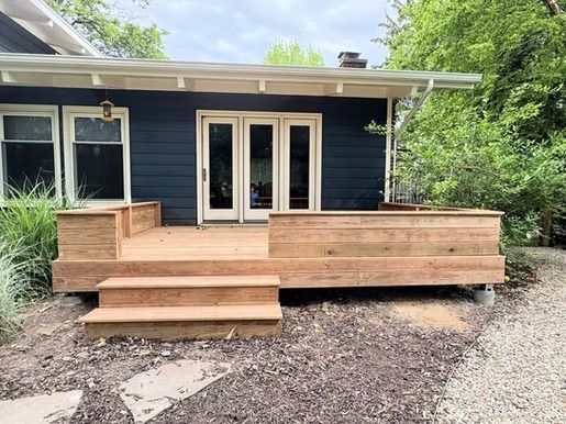 A blue house with a wooden deck in front of it.
