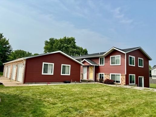 A large red house with a lot of windows is sitting on top of a lush green lawn.