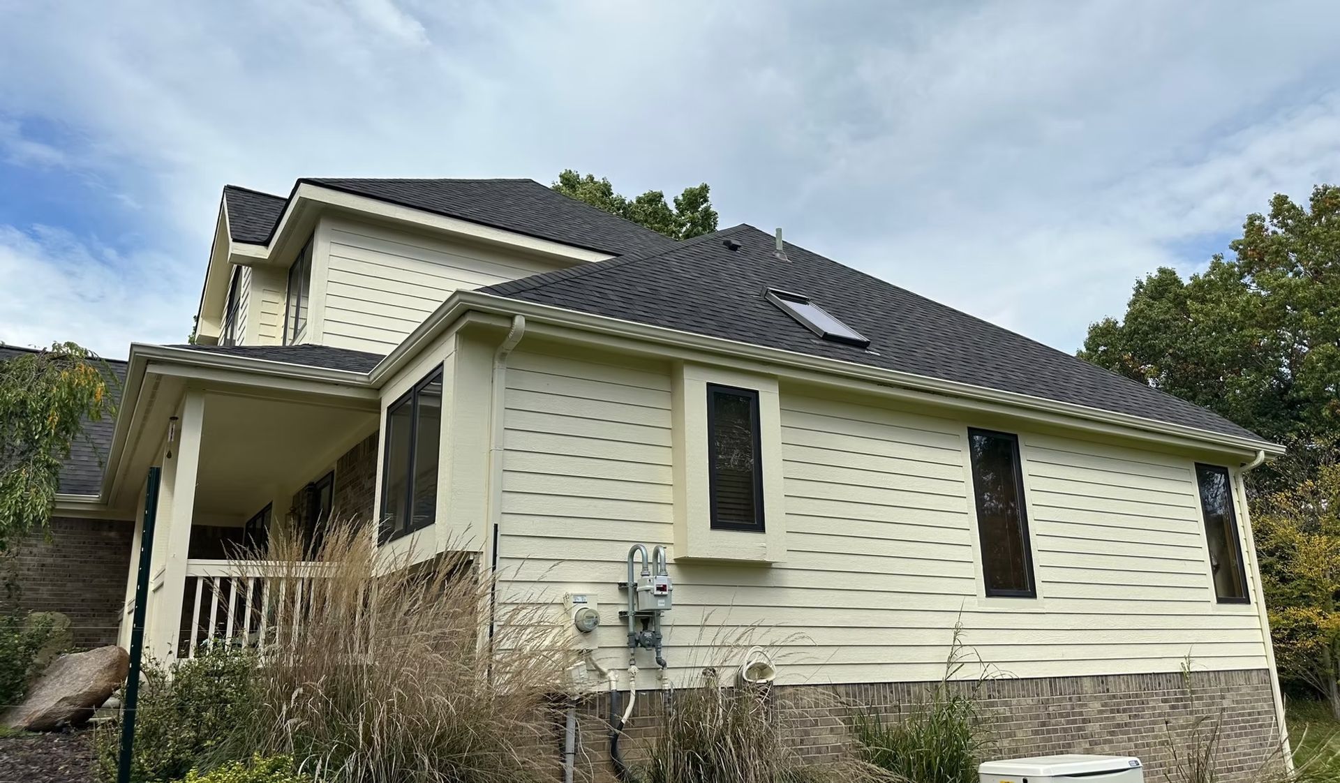A large white house with a black roof is sitting on top of a hill.