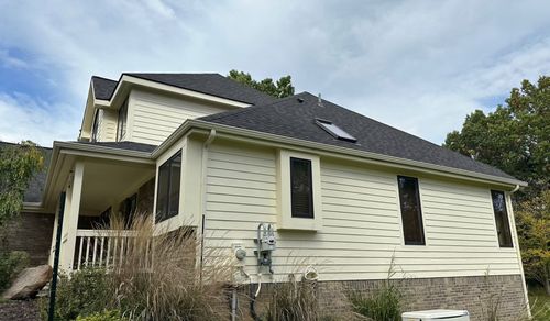 A large white house with a black roof is sitting on top of a hill.
