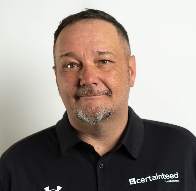 A man with a beard is wearing a black shirt that says certainteed on it.
