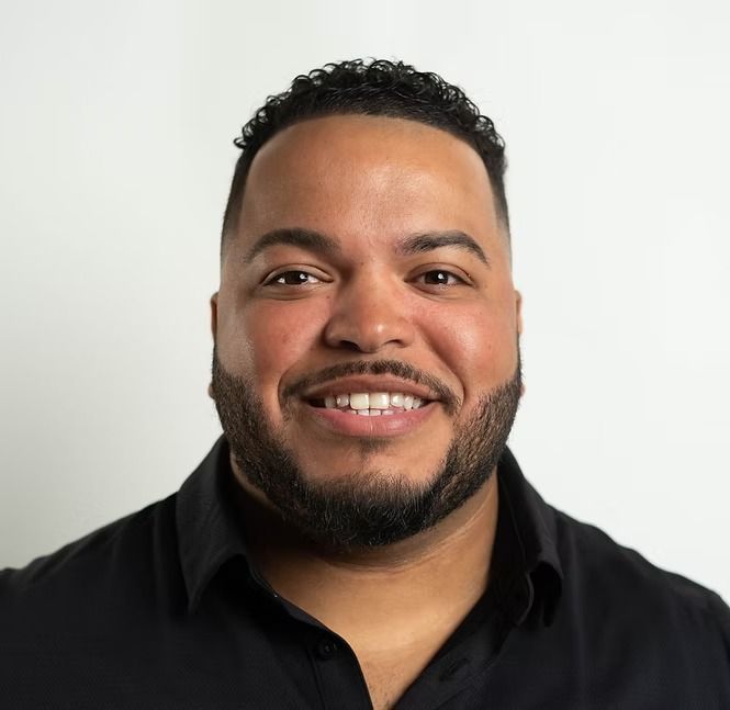 A man with a beard is smiling and wearing a black shirt