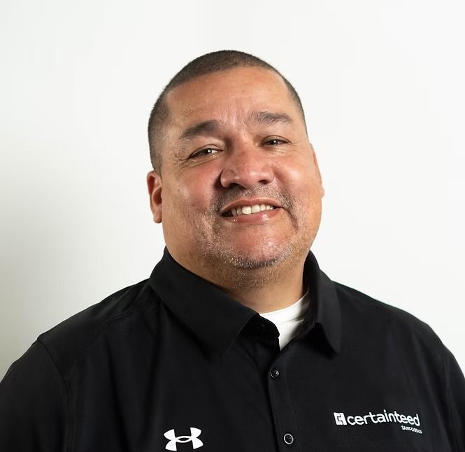 A man wearing a black under armour shirt is smiling for the camera.
