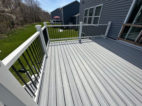 A gray deck with a white railing and a house in the background.