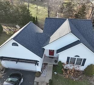 An aerial view of a white house with a black car parked in front of it.