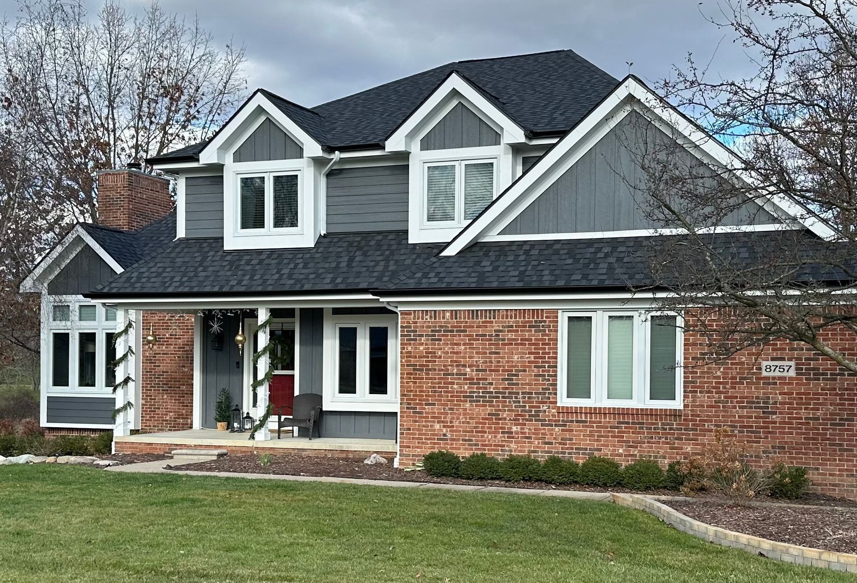 A large brick house with a black roof and white trim.