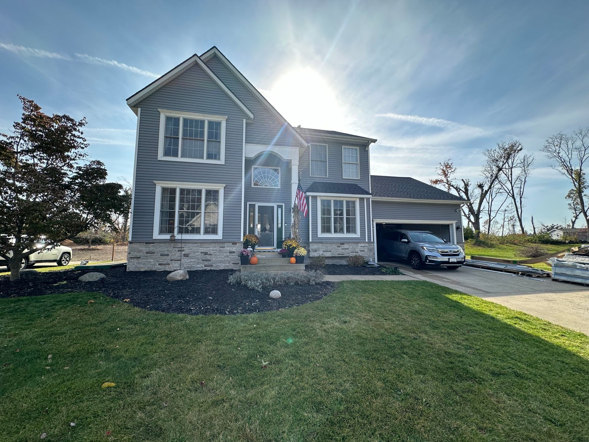 A large gray house with a car parked in front of it.
