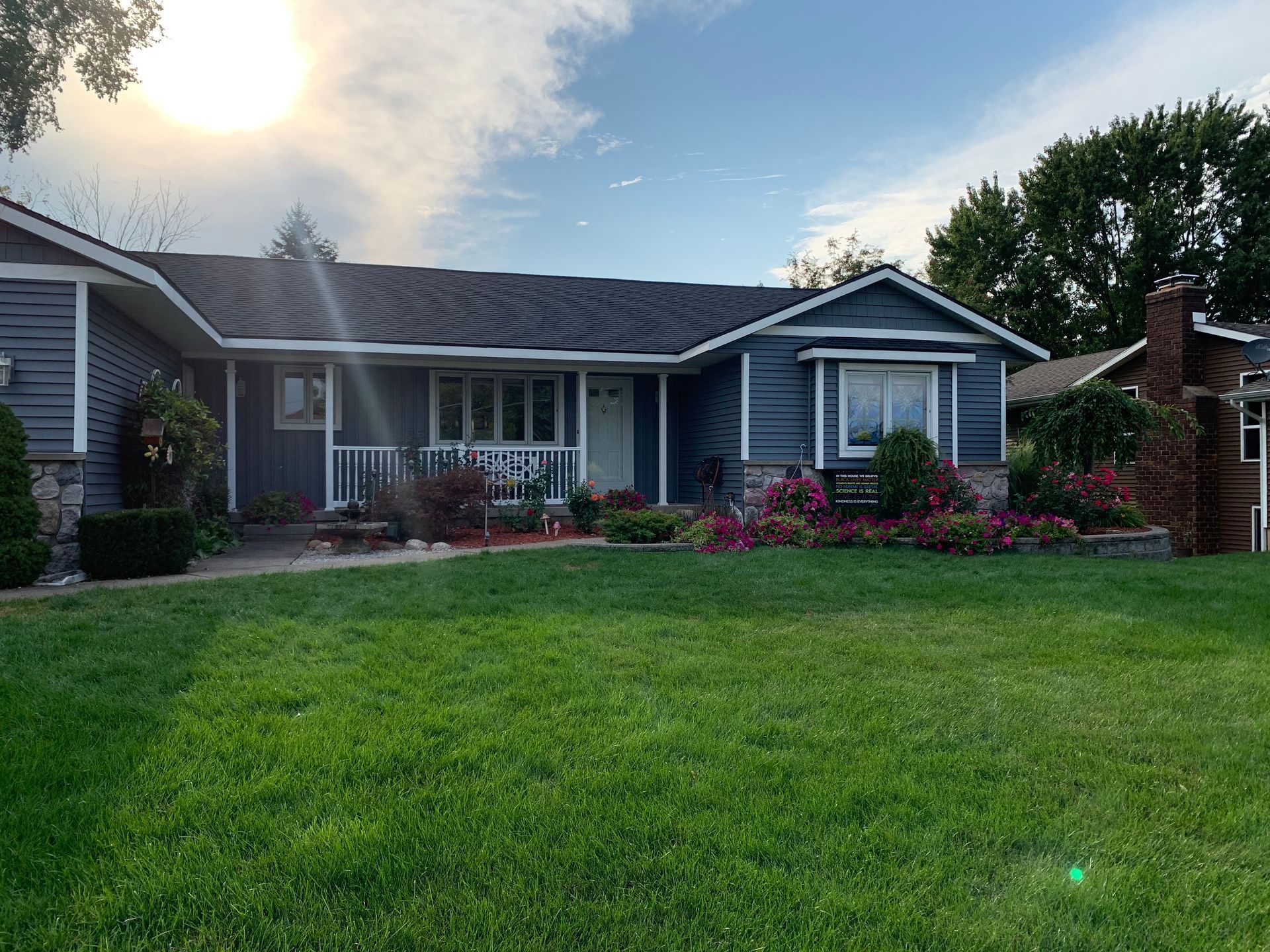 A blue house with a lush green lawn in front of it.