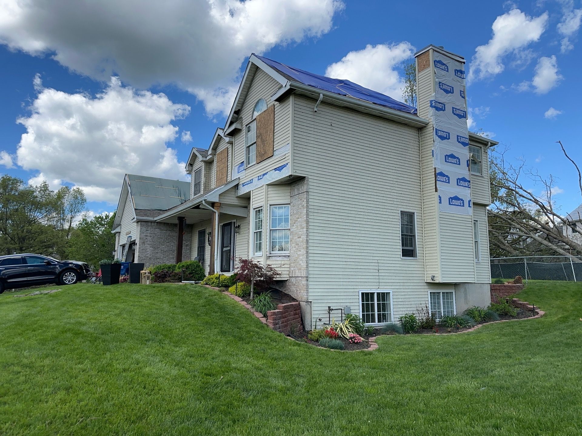 A large white house with a blue roof is sitting on top of a lush green lawn.