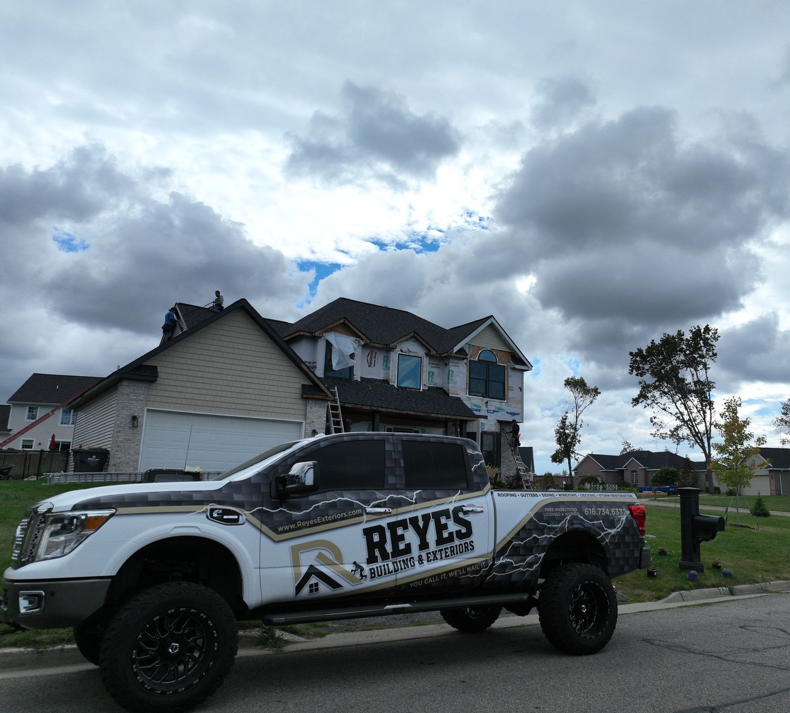 A white truck with reyes written on the side is parked in front of a house