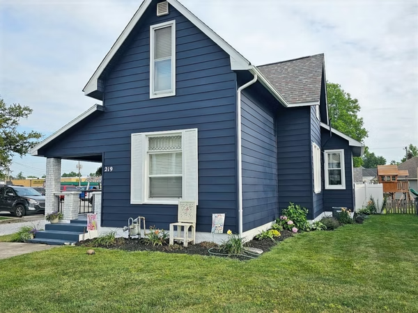 A blue house with white trim and a gray roof
