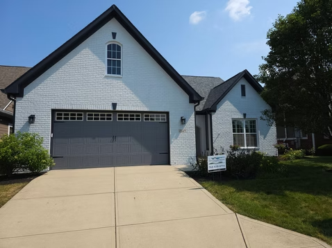 A white house with a gray garage door is for sale