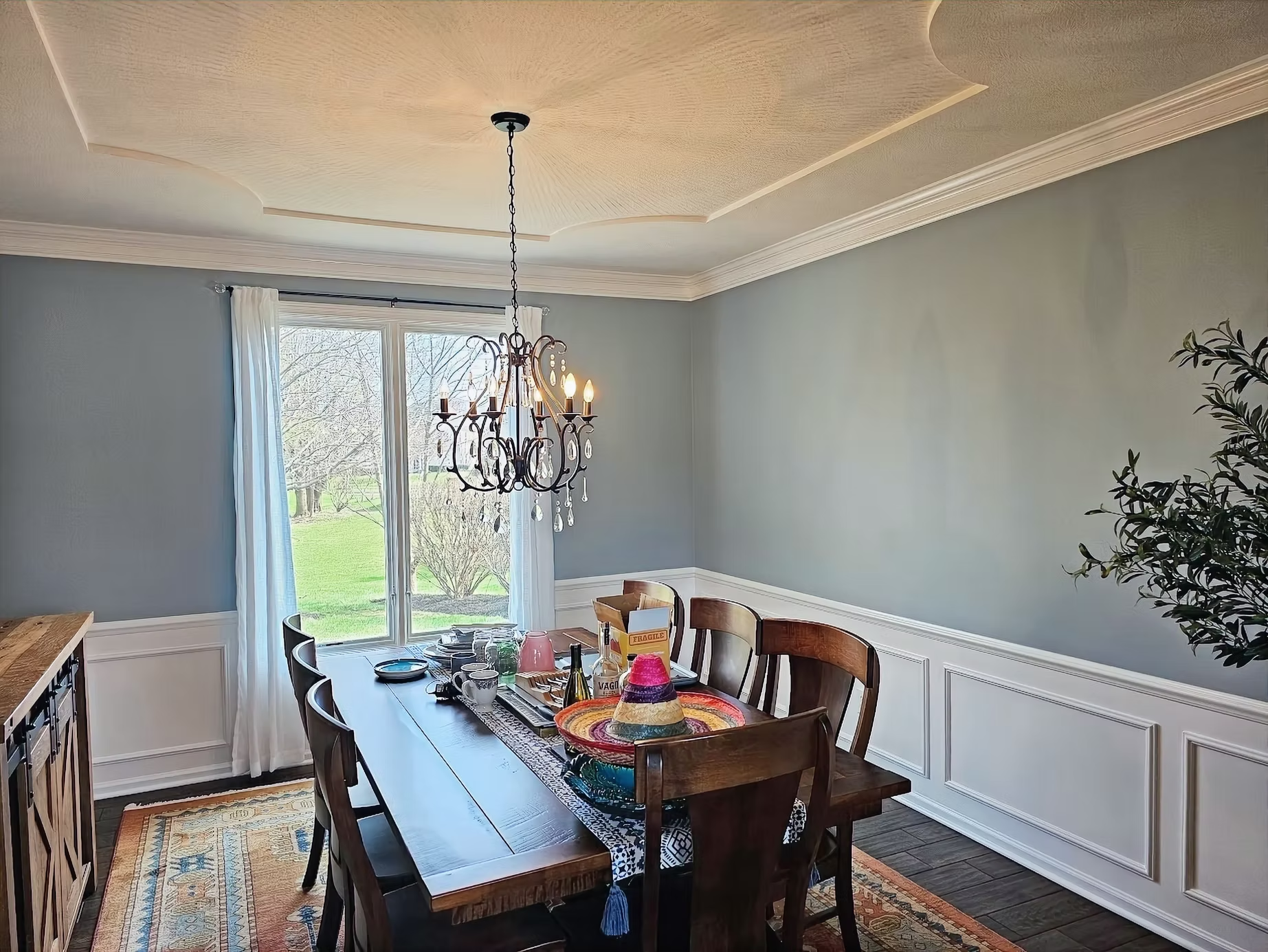 A dining room with a long wooden table and chairs and a chandelier hanging from the ceiling.
