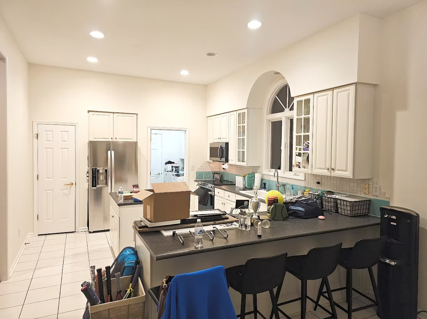 A kitchen with white cabinets , stainless steel appliances , and a large island.