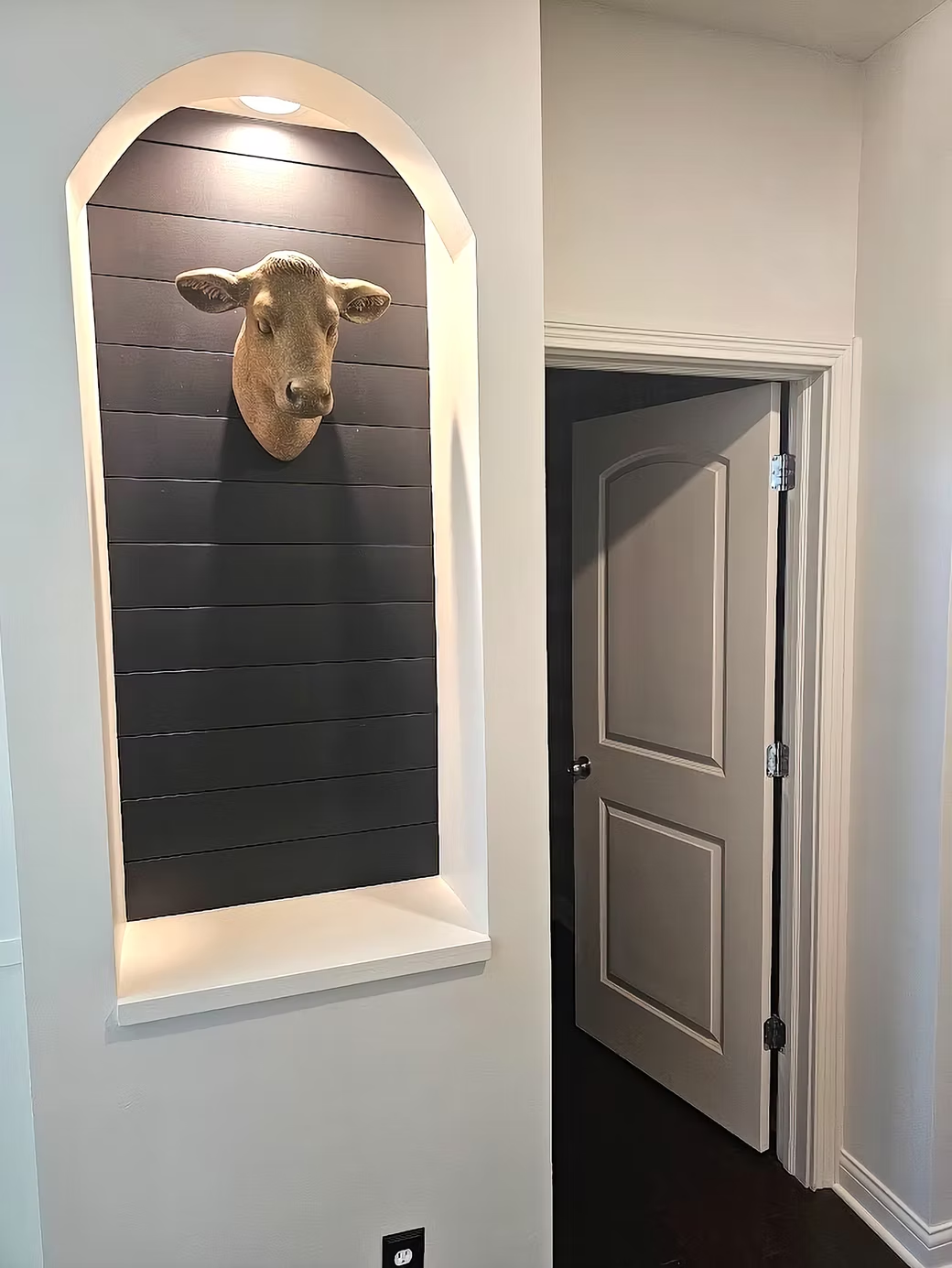 A statue of a sheep 's head is hanging on a wall next to a door