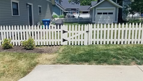 A white picket fence with a gate in front of a house.