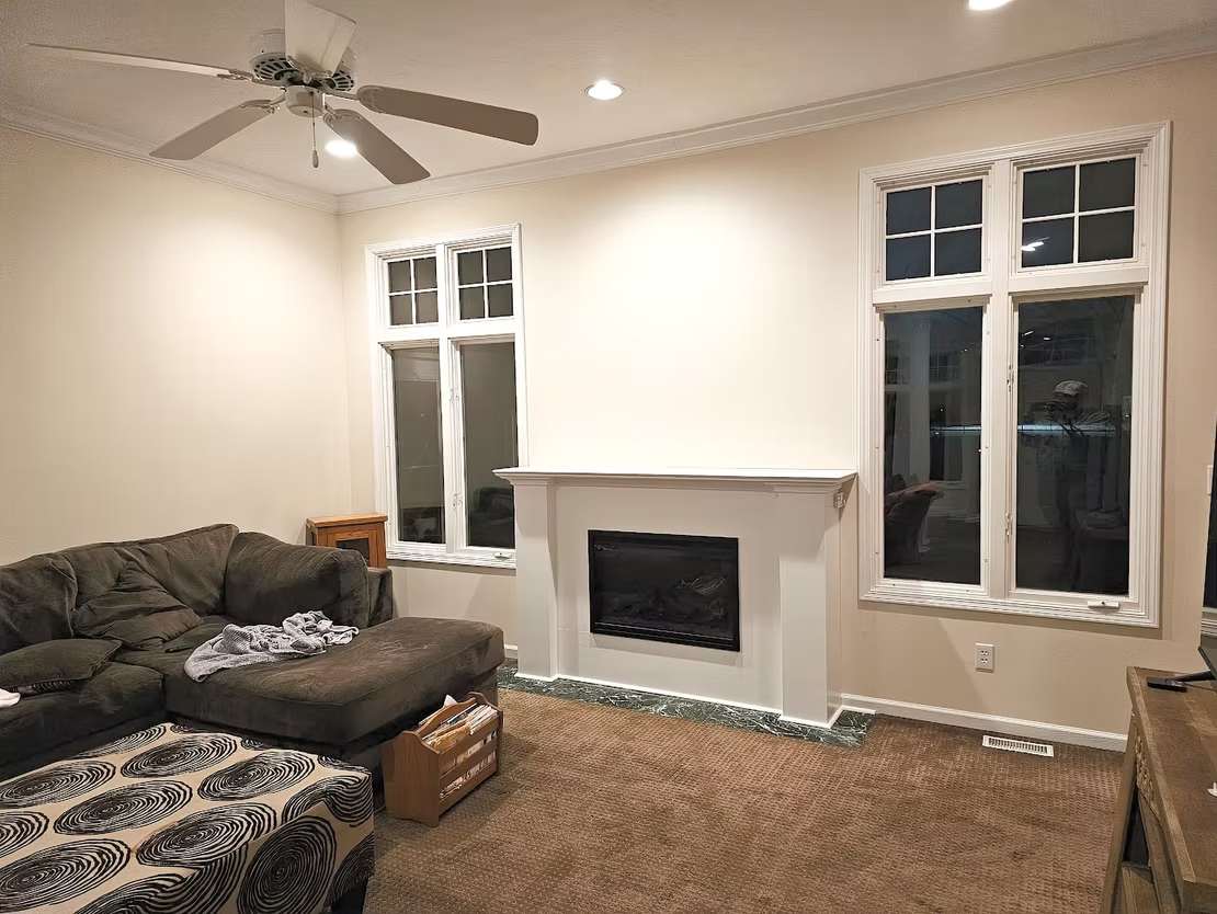 A living room with a couch , fireplace , and ceiling fan.