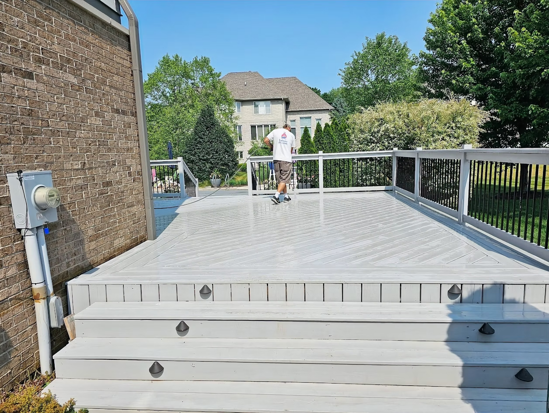 A man is standing on a deck with a house in the background.